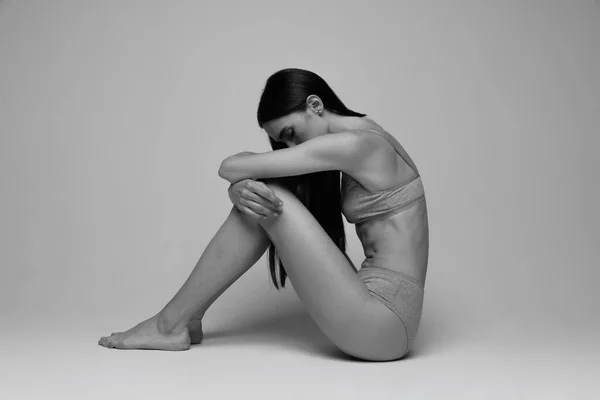 身材苗条 肌肉发达的年轻女子的画像 坐在地板上 穿着内裤 黑白摄影 自然美的概念 身体和皮肤护理 女性气质 自我接纳 — 图库照片