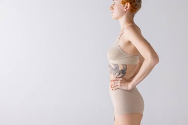 Gri arka planda izole edilmiş bej iç çamaşırlı kadın görüntüsü. El ilanı. Kozmetoloji. Güzellik, vücut ve cilt bakımı, sağlık, estetik cerrahi, ilaç, kozmetik, reklam