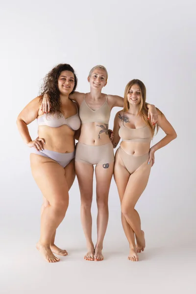 Group portrait of beautiful women posing in underwear isolated over grey studio background. Body-positivity. Concept of beauty, body and skin care, health, plastic surgery, cosmetics, ad