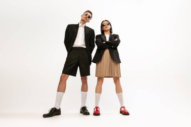 Tarz sahibi genç bir çiftin portresi. Gri stüdyo arka planında izole edilmiş, retro takım elbiseli bir kadın ve erkek. Müsrif moda. Eski moda kavramı, sanat fotoğrafçılığı, stil, nonoş, güzellik.