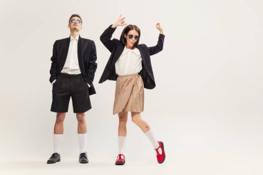 Tarz sahibi genç bir çiftin portresi. Gri stüdyo arka planında izole edilmiş, retro takım elbiseli bir kadın ve erkek. Neşeli dans. Duygular. Eski moda kavramı, sanat fotoğrafçılığı, stil, nonoş, güzellik.