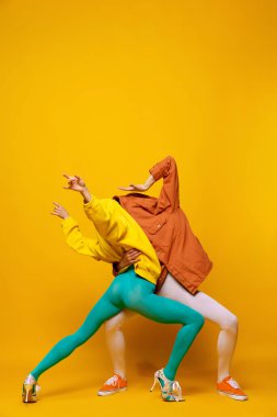 Sarı arka planda izole edilmiş gizli yüzleri olan parlak elbiseli kadın ve erkeğin yaratıcı renkli portresi. Dans ediyorum. Eski moda kavramı, sanat fotoğrafçılığı, stil, nonoş, güzellik.