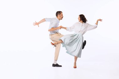 Genç ve neşeli bir çiftin portresi, erkek ve kadın, dans eden boogie woogie beyaz stüdyo arka planında izole edildi. Klasik moda, hobi, aktivite, sanat, müzik, parti, yaratıcılık ve reklam kavramı