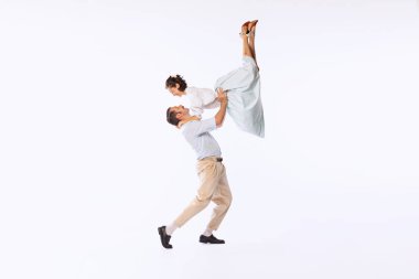 Genç ve güzel bir çiftin portresi, beyaz stüdyo arka planında soyutlanmış bir şekilde dans eden erkek ve kadın. Dans kaldırışı. Klasik moda, hobi, aktivite, sanat, müzik, parti, yaratıcılık ve reklam kavramı