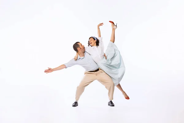 Portrait of young emotive couple, man and woman, dancing retro dance isolated over white studio background. Concept of vintage fashion, hobby, activity, art, music, party, creativity and ad