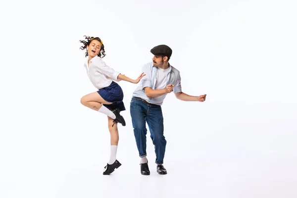 Portrait of beautiful couple, man and woman, dancing retro dance isolated over white studio background. Concept of vintage fashion, hobby, activity, art, music, party, creativity and ad