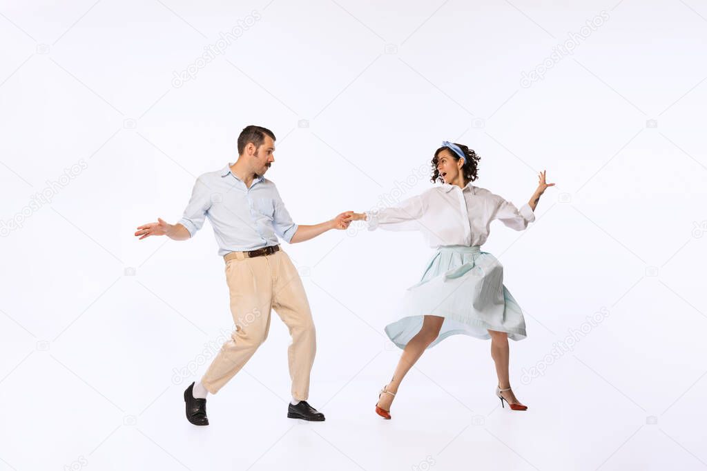 Portrait of young beautiful couple, man and woman, dancing swing isolated over white studio background. Concept of vintage fashion, hobby, activity, art, music, party, emotions, creativity and ad