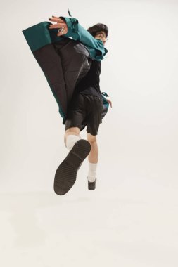 Gri stüdyo arka planında izole edilmiş siyah elbiseli ve yeşil ceketli şık bir gencin portresi. Geriye bakıyorum. Modern moda kavramı, sanat fotoğrafçılığı, stil, nonoşluk, eşsizlik, reklam