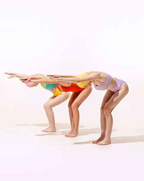 Portrait of three young women in vintage retro swimming suits posing isolated on grey studio background. Ready to dive. Concept of beauty, fashion, vintage style, summertime, party. Copy space for ad