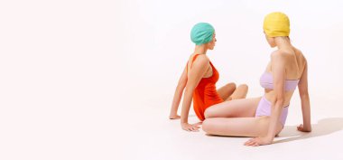 Mayolu ve şapkalı iki genç kadının portresi gri stüdyo arka planında izole edilmiş poz veriyor. Güzellik kavramı, moda, klasik tarz, yaz zamanı, parti. İlan için alanı kopyala