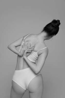 Beyaz iç çamaşırlarıyla poz veren ince vücutlu genç bir kızın portresi. Siyah beyaz fotoğrafçılık. Vücut estetiği. Doğal güzellik kavramı, vücut ve cilt bakımı, kadınlık, kendini kabullenme, reklam