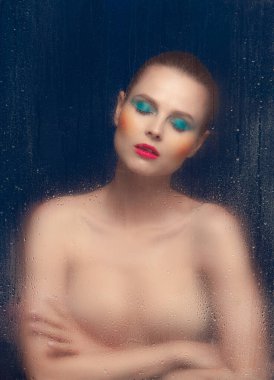 Portrait of beautiful woman with bright makeup posing in underwear isolated over dark blue background. Foggy glass effect. Concept of beauty, fashion, style, cosmetology, cosmetics. Copy space for ad