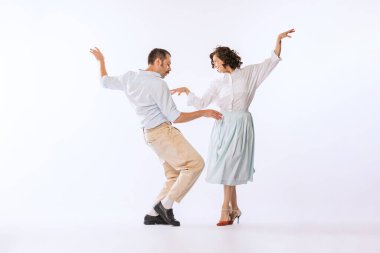 Genç ve güzel bir çiftin portresi, beyaz stüdyo arka planında soyutlanmış bir şekilde dans eden erkek ve kadın. Coşkulu bir dans. Klasik moda, hobi, aktivite, sanat, müzik, parti, yaratıcılık ve reklam kavramı