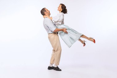 Portrait of young beautiful couple, man and woman, dancing isolated over white studio background. Vintage lifestyle. Concept of retro fashion, hobby, activity, art, music, party, creativity and ad