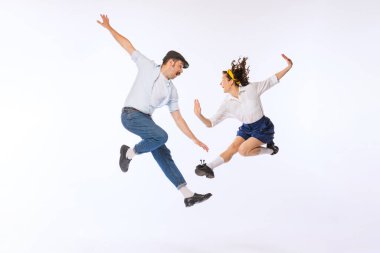Genç ve güzel bir çiftin portresi, erkek ve kadın, beyaz arka planda izole bir şekilde dans eden modaya uygun retro giysiler içinde. Klasik moda, hobi, aktivite, sanat, müzik, parti, yaratıcılık ve reklam kavramı