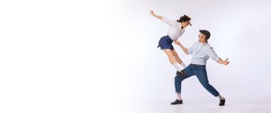 Genç ve güzel bir çiftin portresi, beyaz stüdyo arka planında izole dans eden erkek ve kadın. Lindy Hop. Klasik moda, hobi, aktivite, sanat, müzik, parti, yaratıcılık ve reklam kavramı