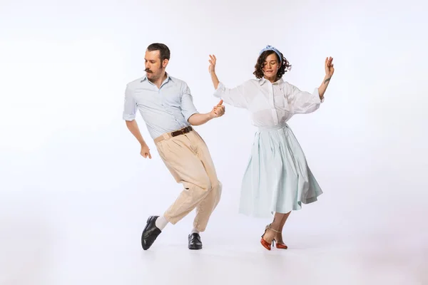 Portrait of young cheerful couple, man and woman, dancing isolated over white studio background. Disco party. Concept of vintage fashion, hobby, activity, art, music, party, creativity and ad
