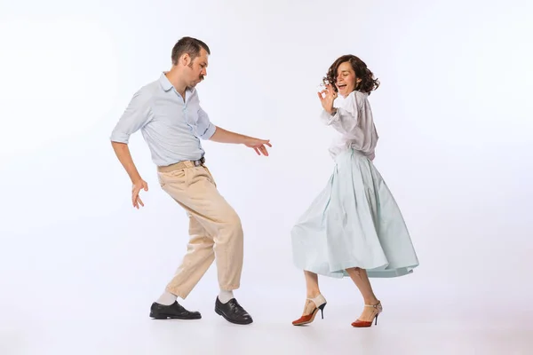 Portrait of young beautiful couple, man and woman, dancing isolated over white studio background. Romantic date. Concept of vintage fashion, hobby, activity, art, music, party, creativity and ad