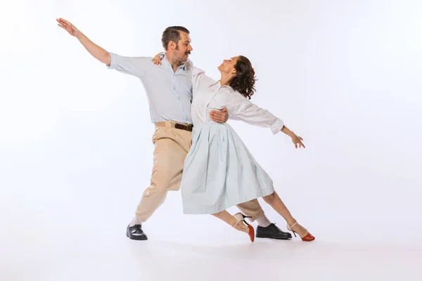 Portrait of young beautiful couple, man and woman, dancing isolated over white studio background. Tender dance. Concept of vintage fashion, hobby, activity, art, music, party, creativity and ad