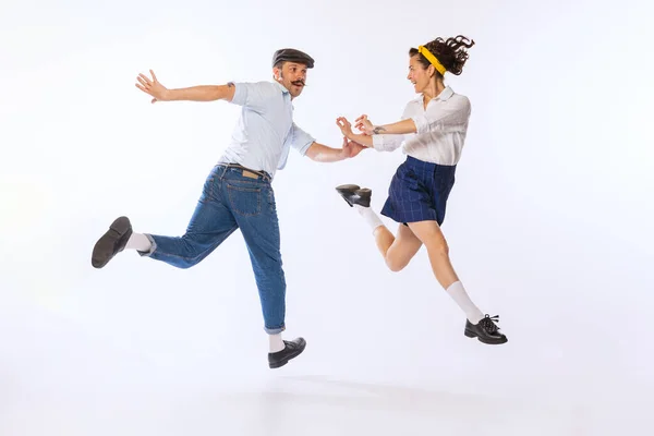 Portrait of young beautiful couple, man and woman, dancing retro dance isolated over white background. Cheerful hobby. Concept of vintage fashion, hobby, activity, art, music, party, creativity and ad