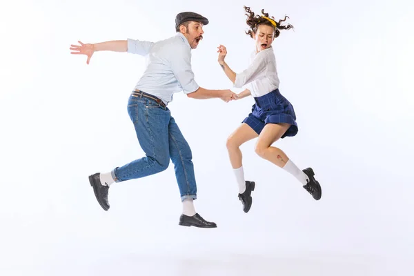 Portrait of young emotive couple, man and woman, dancing retro dance isolated on white studio background. Ralaxation. Concept of vintage fashion, hobby, activity, art, music, party, creativity and ad