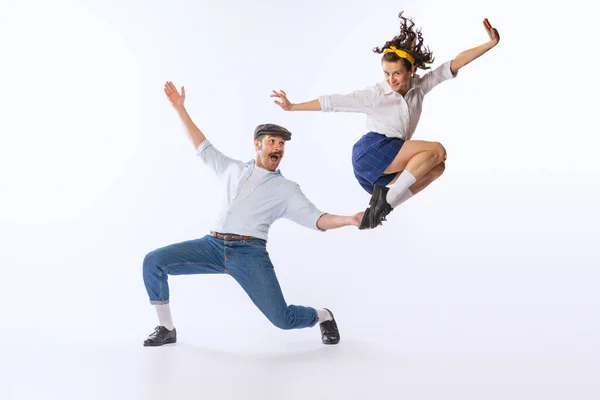 Portrait of young happy couple, man and woman, dancing isolated over white studio background. Excitement. Concept of vintage fashion, hobby, activity, art, music, party, creativity and ad