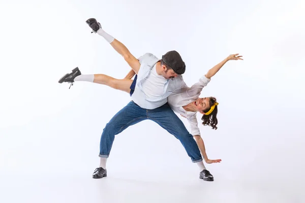 Portrait of young beautiful couple, man and woman, dancing isolated over white background. Extravagant dance moves. Concept of vintage fashion, hobby, activity, art, music, party, creativity and ad