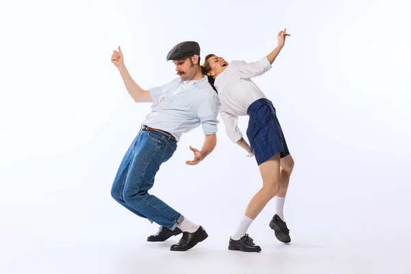 Portrait of young beautiful couple, man and woman, dancing retro dance isolated over white studio background. Vibe . Concept of vintage fashion, hobby, activity, art, music, party, creativity and ad
