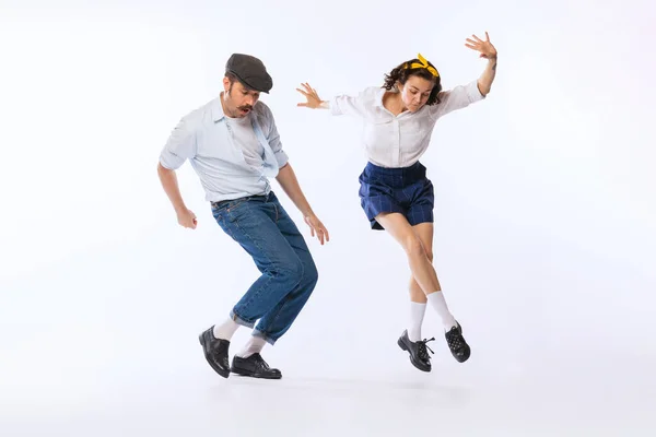Portrait of young beautiful couple, man and woman, dancing boogie woogie isolated over white studio background. Concept of vintage fashion, hobby, activity, art, music, party, creativity and ad
