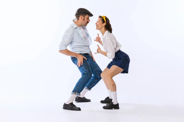 Portrait of young beautiful couple, man and woman, dancing twist isolated over white studio background. Concept of vintage fashion, hobby, activity, art, music, party, creativity and ad