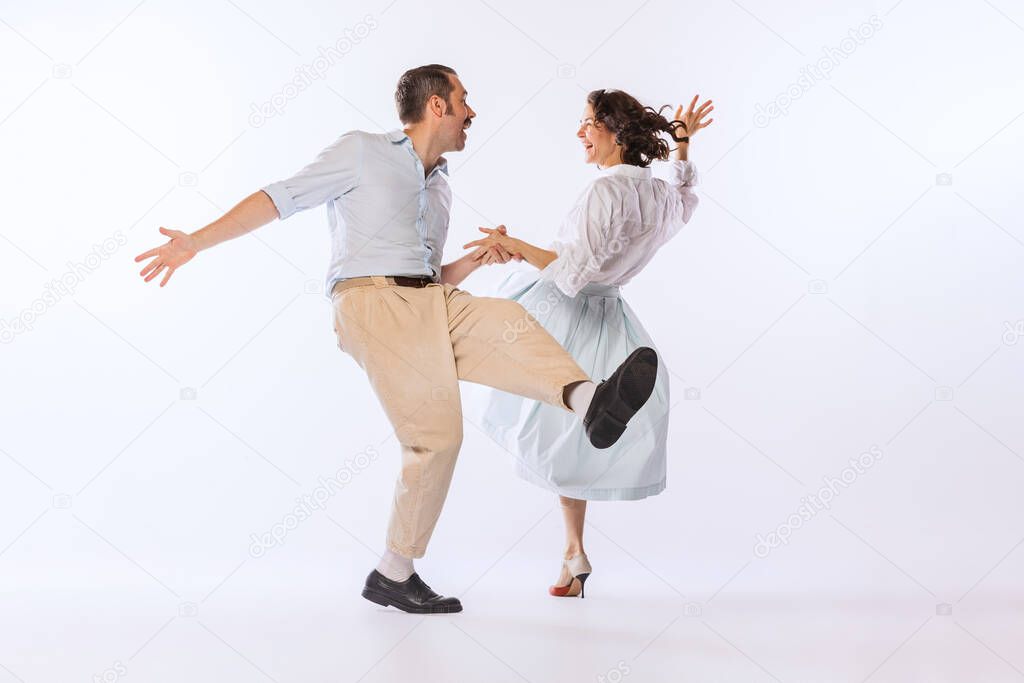 Portrait of young stylish couple, man and woman, dancing isolated over white studio background. Classic dance styles. Concept of vintage fashion, hobby, activity, art, music, party, creativity and ad