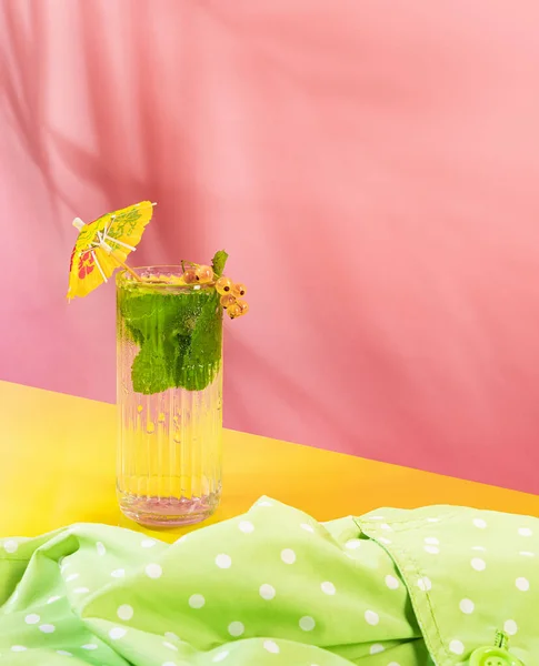 Glass of chill sparkling water, mojito cocktail with fresh mint, lime and rom isolated on pink background. Summer drink. Concept of alcoholic drinks, taste, party, mix. Copy space for ad. Retro style
