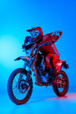Motosiklet süren genç bir adamın portresi. Mavi renkli arka plan üzerinde izole edilmiş. Spor eğitimi. Motosport, hız, aksiyon, hobi, rekabet kavramı. İlan için alanı kopyala