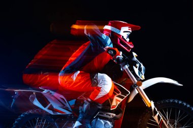 Motosiklet süren genç bir adamın portresi. Siyah arka planda izole edilmiş, neon ışıklı. Dinamik. Motosport, hız, aksiyon, hobi, rekabet kavramı. İlan için alanı kopyala