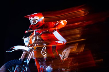 Genç adamın portresi, motosikletli tam teçhizatlı motosikletli siyah stüdyo arka planında izole edilmiş, karışık ışıklandırmalı. Motosport, hız, aksiyon, hobi, rekabet kavramı. İlan için alanı kopyala