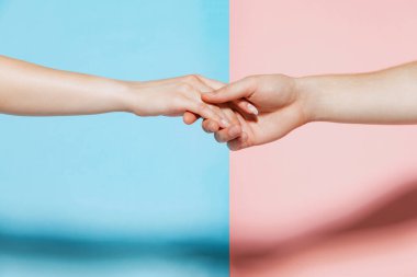 Image of male and female hands reaching each other, holding isolated over pink blue studio background. Support. Concept of youth, emotions, facial expression, love, relationship. Poster, ad