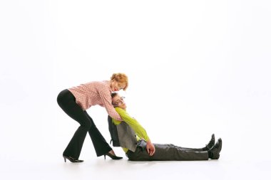 Stylis young woman pulling fainted man isolated over white studio background. Emotive soul, expressive news. Concept of retro fashion, style, youth culture, emotions, beauty. Copy space for ad