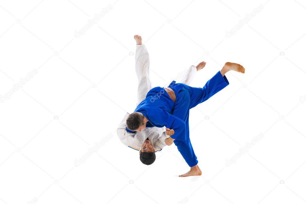 One-arm shoulder throw. Studio shot of two men, professional judo athletes training isolated on white background. Concept of martial art, combat sport, health, strength, energy, fit. Copy space for ad