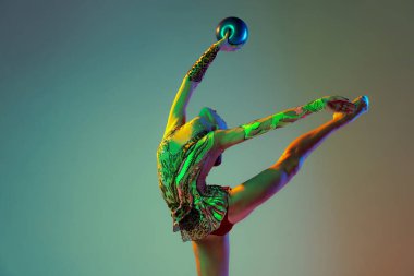 Portrait of young girl, rhythmic gymnast athlete training with ball isolated on multicolored background in neon light. Concept of action, motion, sport life, motivation, competition. Copyspace for ad