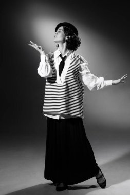 Portrait of beautiful tender woman in stylish classical clothes, striped vest and hat posing. Black and white photography. Haute couture. Elegance. Monochrome effect. Fashion, style, history concept