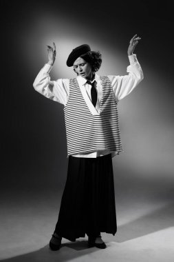 Portrait of beautiful emotive woman in stylish classical clothes, jacket and hat tenderly posing. Black and white photography. Elegance and grace. Monochrome effect. Concept of fashion, style, history