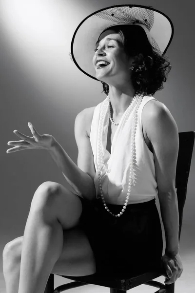 Portrait of beautiful woman in character of famous fashion designer posing in stylish classic suit. Black and white photography. Tender laugh. Monochrome effect. Concept of fashion, style, history