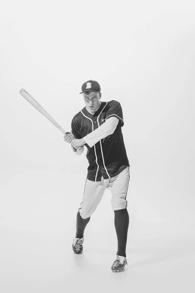 Young man, baseball player, batter ready to hit ball with bat. Black and white photography. Concentration and motivation. Concept of sport, retro style, 20s, fashion, action, college sport, youth