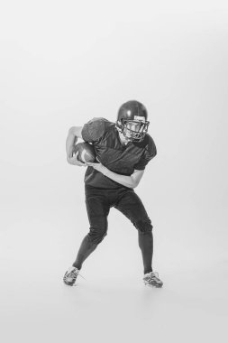Portrait of young man, college student, american football player during game. Black and white photography. Winning game. Concept of sport, retro style, 20s, fashion, action, college sport, youth