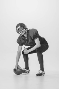 Portrait of young smiling man, american football player posing. Black and white photography. After winning match. Concept of sport, retro style, 20s, fashion, action, college sport, youth
