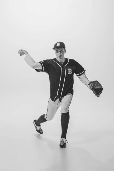 Portrait of young man, college student, baseball player, pitcher training, serving ball. black and white photography. Concept of sport, retro style, 20s, fashion, action, college sport, youth