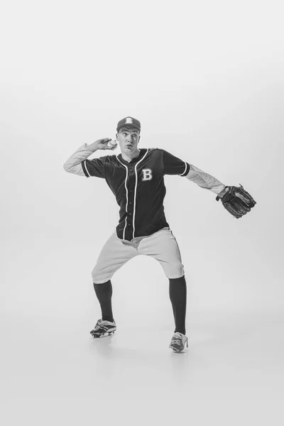 Portrait of concentrated man, college student, baseball player, pitcher training, serving ball. black and white photography. Concept of sport, retro style, 20s, fashion, action, college sport, youth