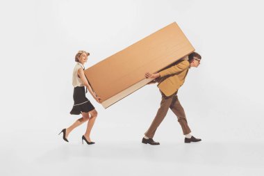 Young man and woman carrying big cardboard boxes isolated over white background. Black Friday shopping, sales, moving. Concept of retro fashion, style, youth culture, emotions, relationship, ad