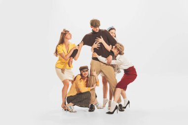Group of young beautiful women hugging, cathing young man isolated over white studio background. Bachelor. Concept of retro fashion, style, youth culture, emotions, beauty, relationship, ad