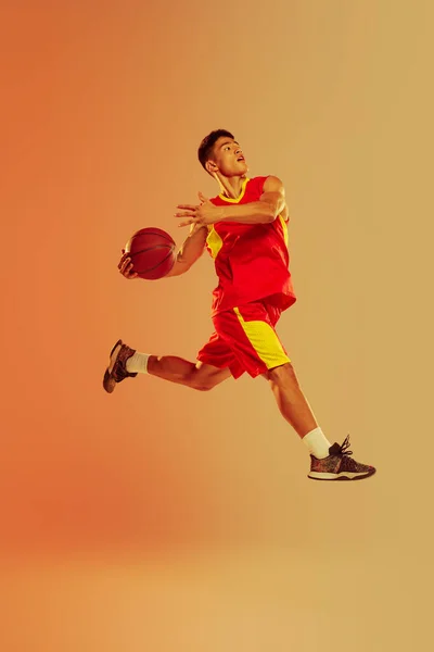 Динамичный Портрет Молодого Человека Баскетболиста Бросающего Мяч Корзину Изолированного Оранжевом — стоковое фото